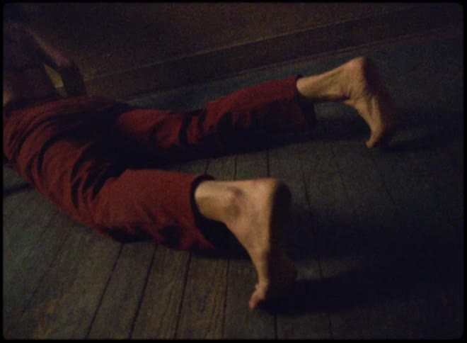 A woman is rolling on the floor in a dark room while wearing red cloth