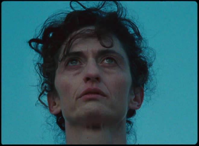 A zoom in of a womans face as she stands looking forward with tears in her eyes