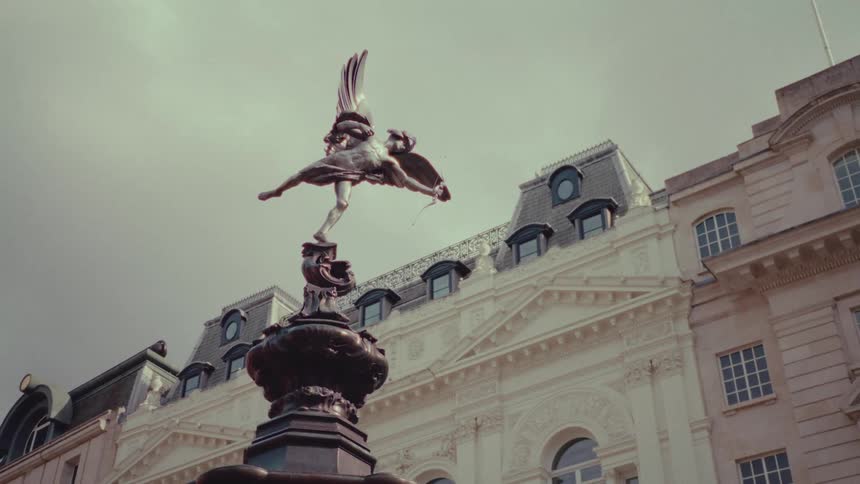 An angel statue in front of buildings in a european city on a cloudy day