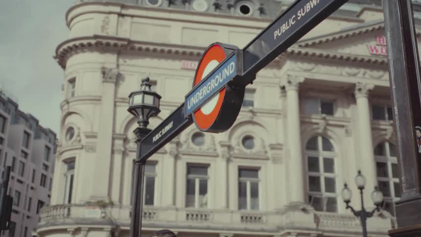 The underground subway street sign that is made from steel next to a building painted white