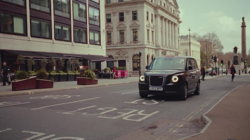 A vehicle travels along a street in a city during the day