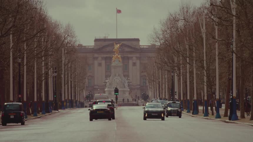 Cars drive on the road with a statue at the end