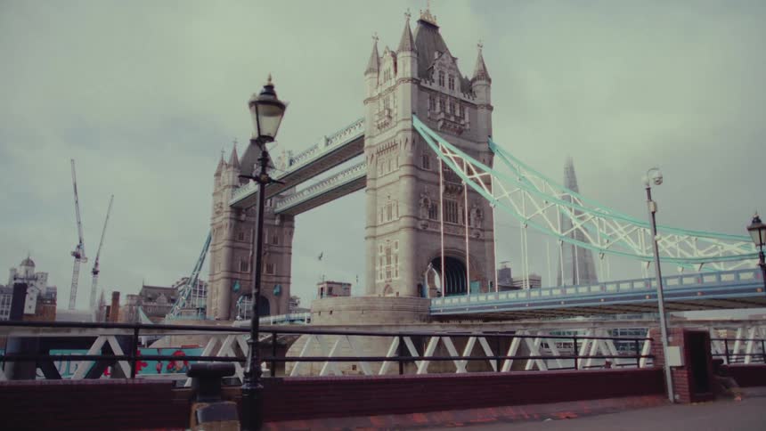 On a welllit street a handrail is visible with the iconic london bridge in the distance