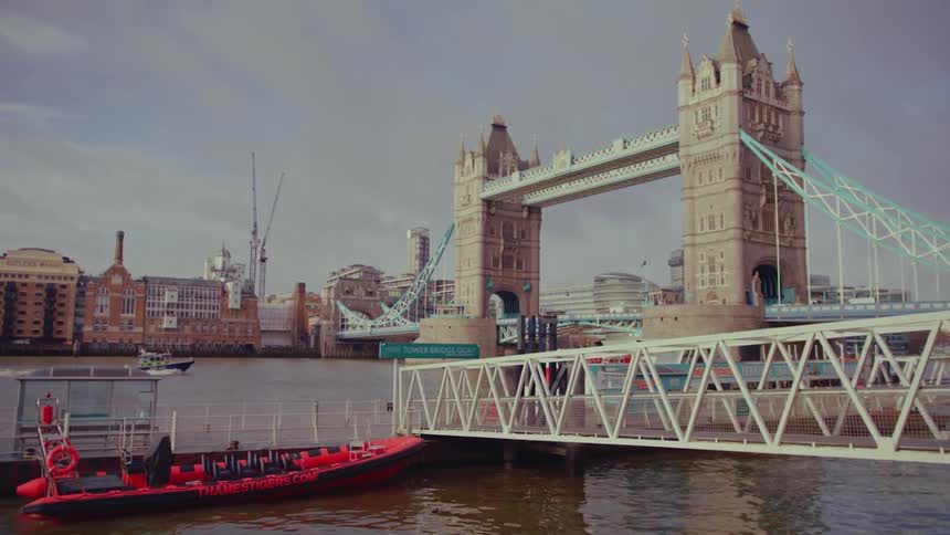 Traffic crosses historic london bridge as boat motors along river