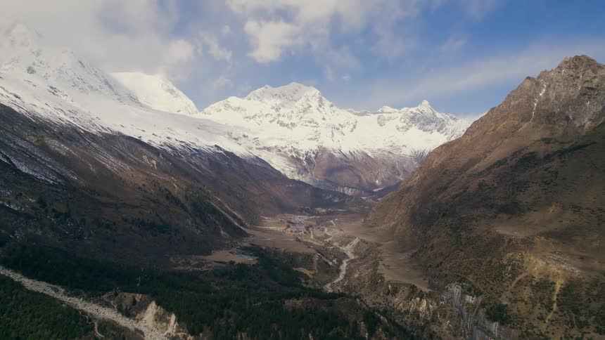 An aerial view of a valley and snow capped mountains