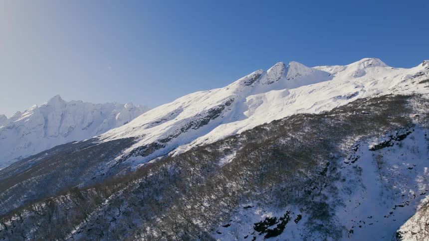 Aerial view of snowy mountain slope against the blue sky