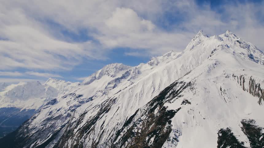 The mountain is having rough terrain and is covered with snow on a clear sunny day