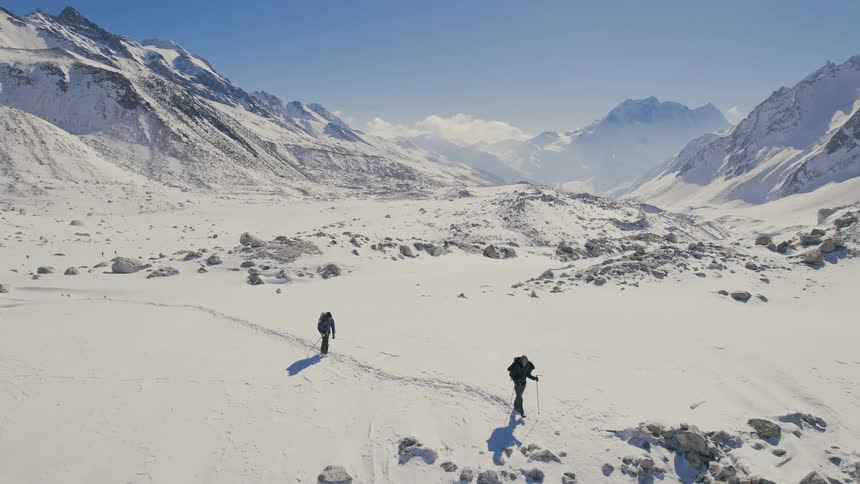 Two people are hiking through the snow on the mountain