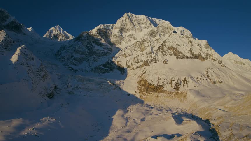 A towering rocky mountain is covered with snow under a clear sky
