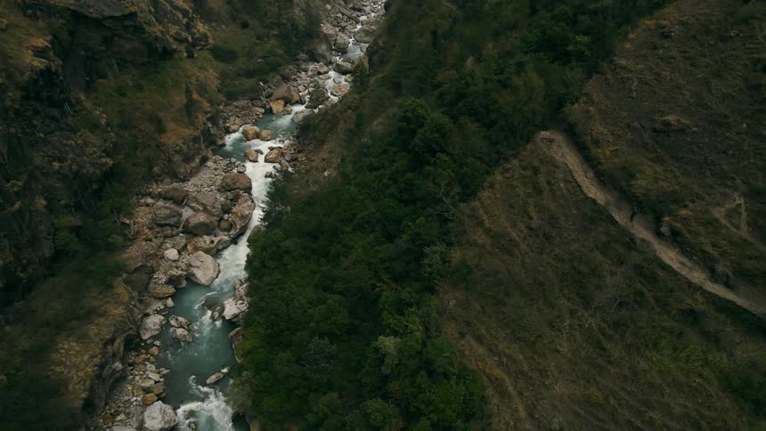 Aerial view of a ravine between mountains with a person walking on a path in the mountain