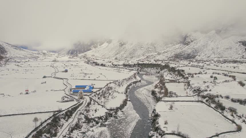 Aerial of a blue building in the snowcovered valley near a river