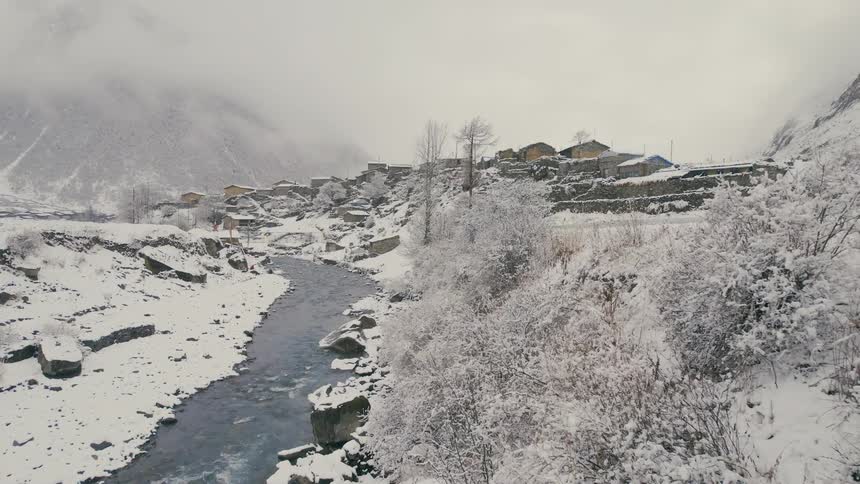 An aerial view of a river that flows in a valley near a mountain village community