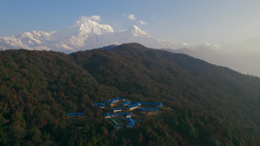 A number of buildings with blue roofs are high up on a mountain