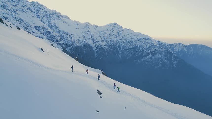 A group of people walking up a snowy mountain path to reach a resort at the top