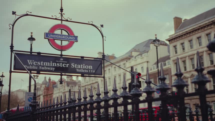 Underground westminster subway sign on the sidewalk with a steel fence and buildings lining the other side of the road