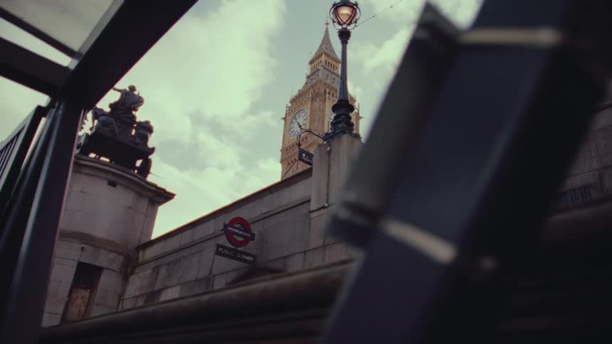 Big ben clock tower in view with a horsemounted monument atop a fence while walking on a walkway