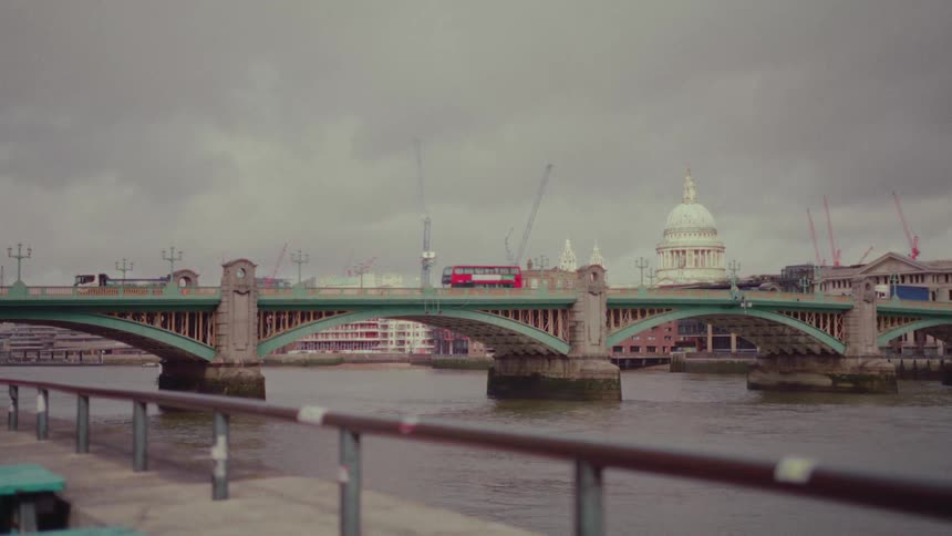 A bridge with traffic over a river in a city on a cloudy day