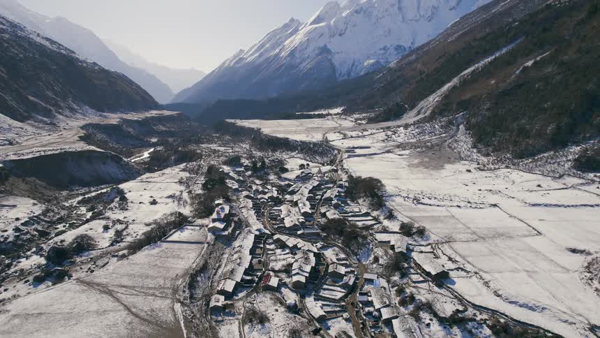 A rural town covered in snow and surrounded by fields and mountains