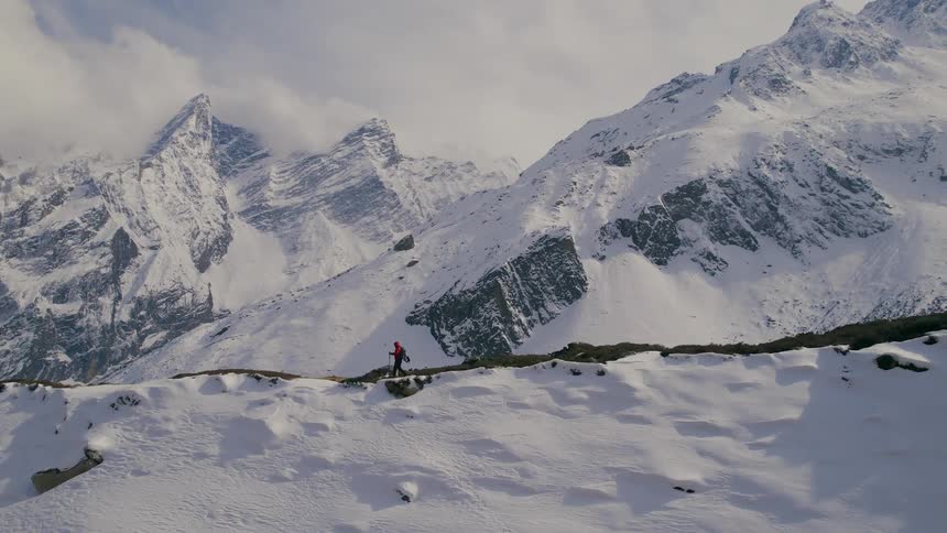 A person hiking at the summit of a snowcovered mountain during the day