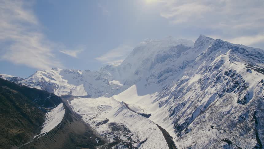 An aerial of snow covered mountain ranges on a bright sunny day