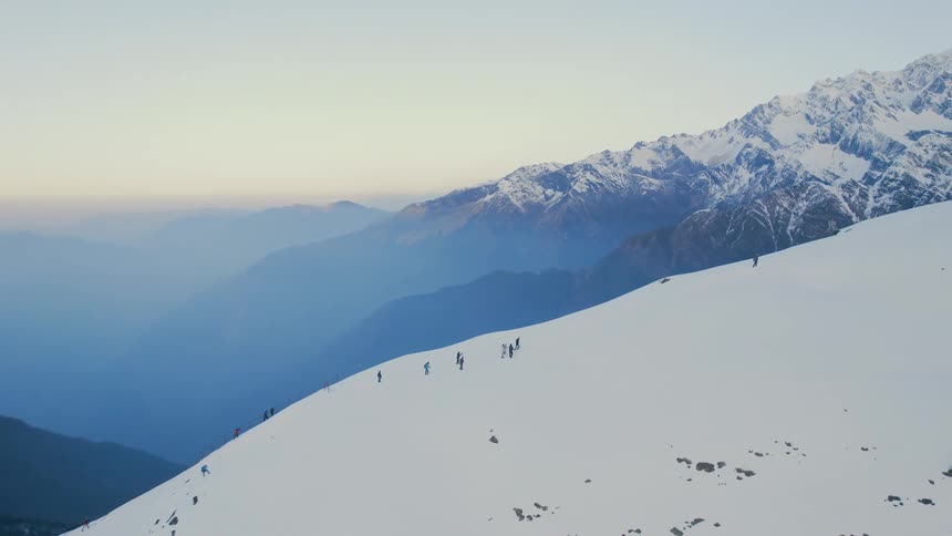 Aerial of a group of people climbing the snowcovered slopes of a mountain