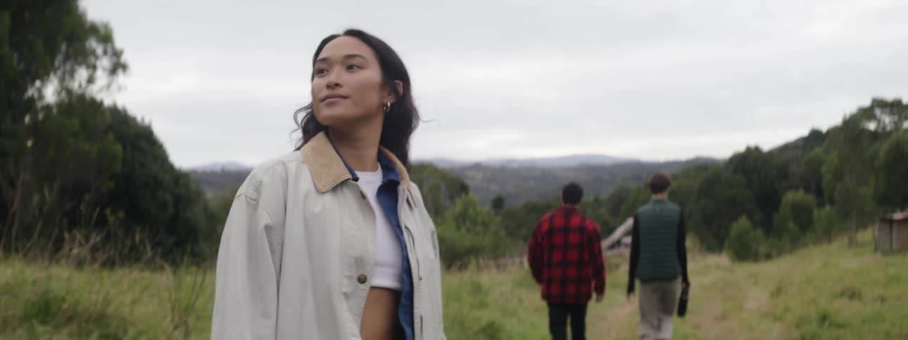 A young woman looks around the countryside while walking behind her friends
