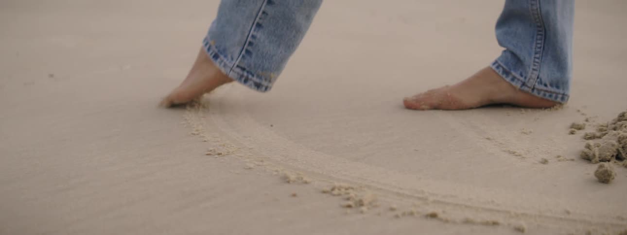 A pair of mans feet drawing on a beachs sand