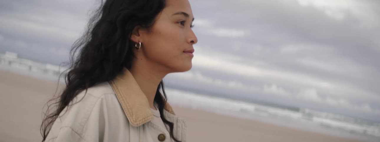 A woman walks on a beach and runs her toes through the sand
