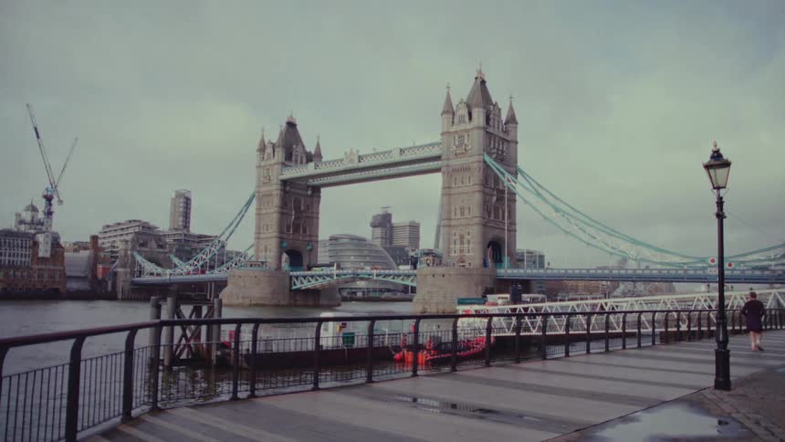 A person jogging on a sidewalk near a bridge and a river