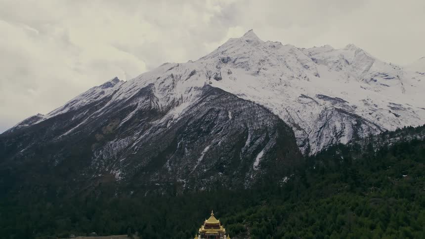 A temple with golden roof surrounded by a mountain covered in snow