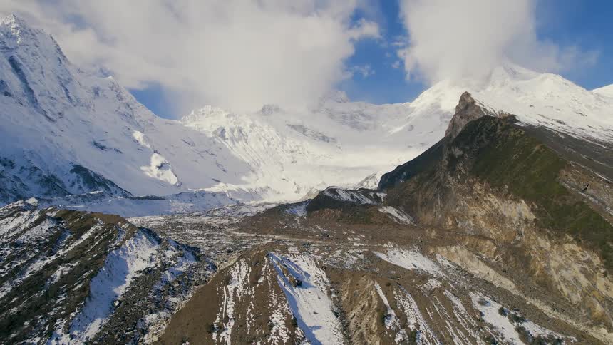 A mountain range is partially covered in snow on a sunny day