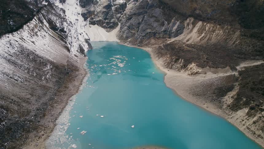 A bright blue river at the base of a cliff
