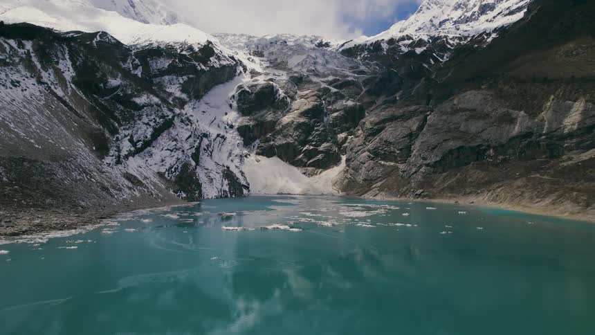 A frozen lake at the base of a mountain during the day
