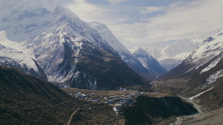 A village in a valley surrounded by mountains with snow