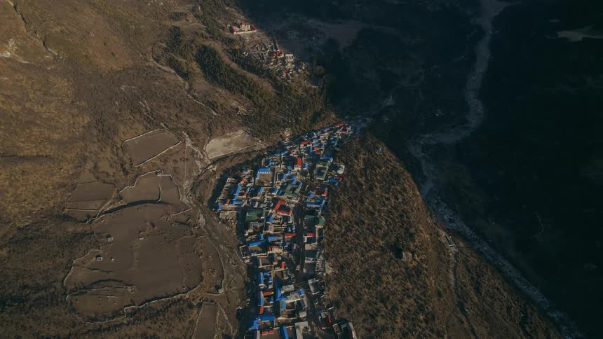 Aerial of colorful roofs on houses in a rural community near a mountain shadow