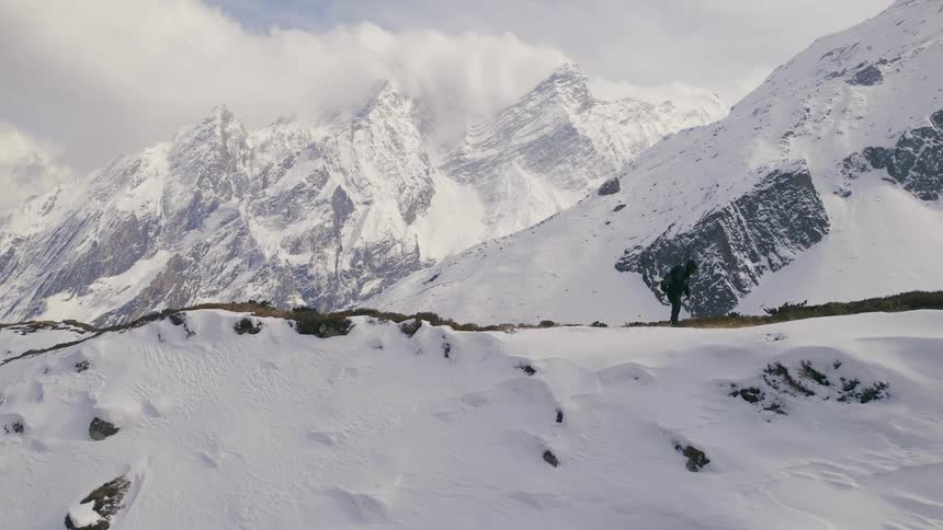 A lone hiker makes their way along a snowcovered mountain ridge