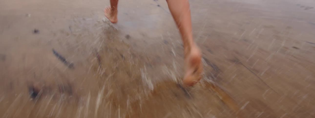 A woman in a bikini runs along a beach during the day