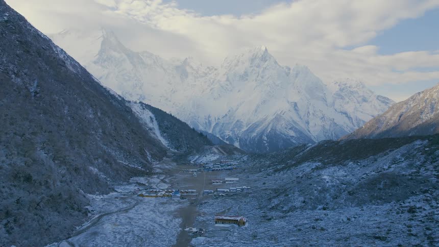 Aerial landscape of a valley with many small buildings next to an icy mountain