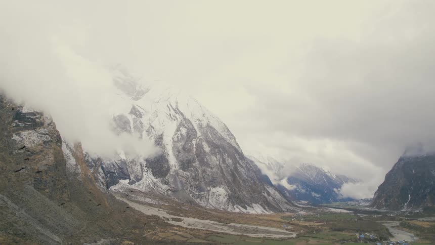 Aerial of birds flying near the snow covered mountains under white clouds