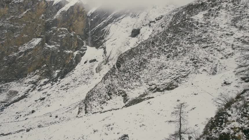An aerial view of a snowcovered mountain range with a valley in the middle and a waterfall in the distance