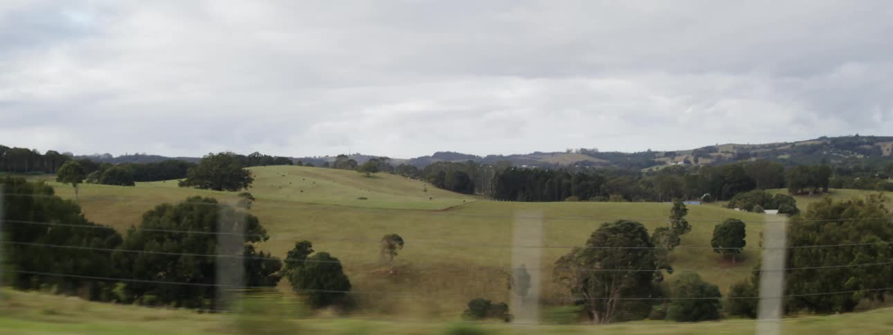 Fence line and roadsides panning by quickly looking out over hillsides and valleys covered in trees