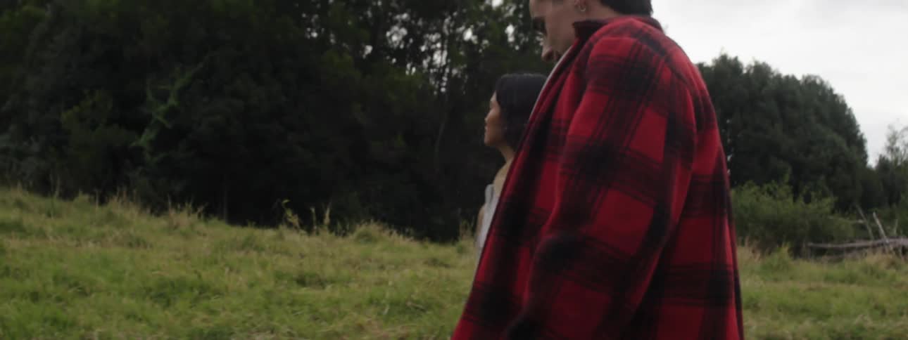 Two young men and a woman walk across a grassy field