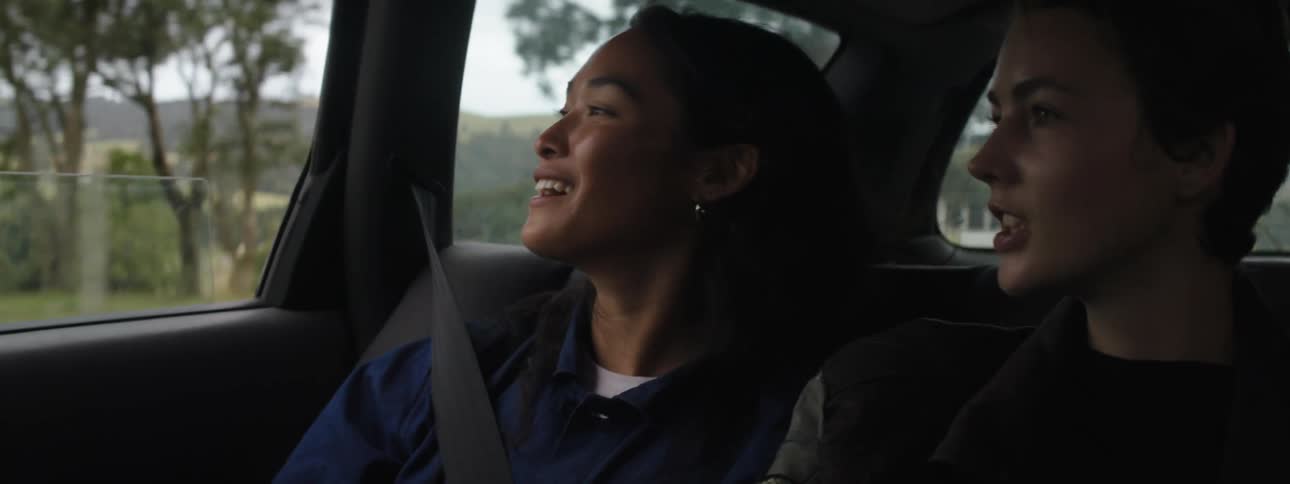 Two women sitting in the back of a vehicle traveling down the road