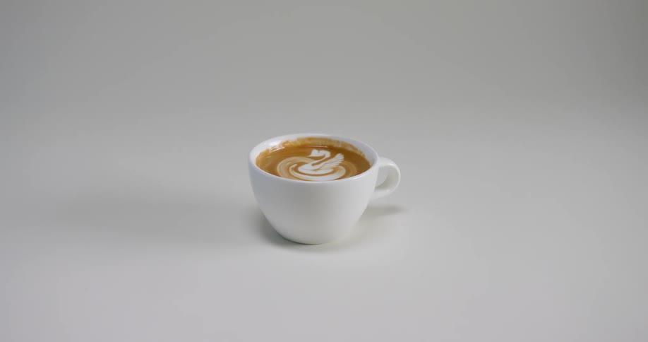 A small cup of a caffeinated beverage sits atop a white surface