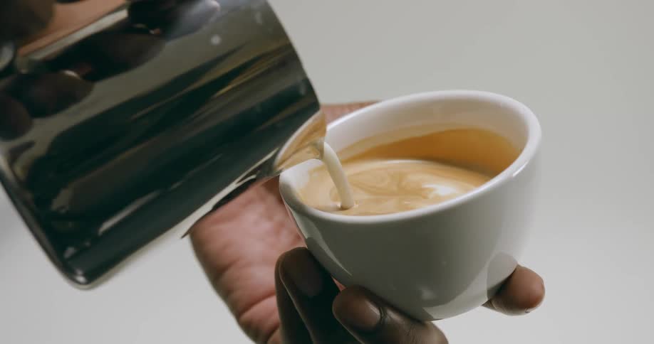Male hands pouring milk into a cup of coffee
