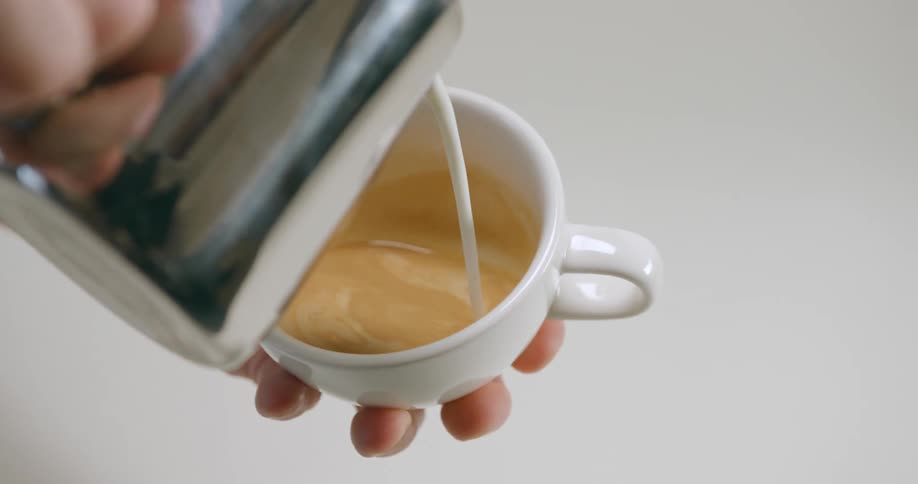 Man pouring milk from a jar into a cup of coffee
