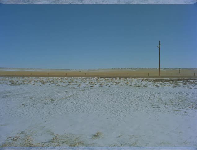 Truck drives past fields one snow covered the other browned grass