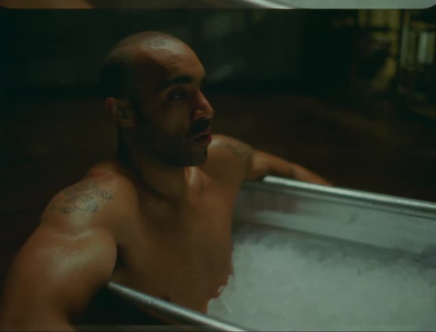 Man soaks in ice filled metal tub in middle of floor