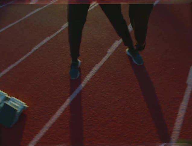 A man stretches out and touches his toes on an outdoor track