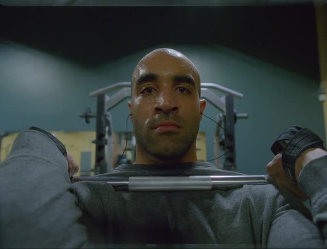 A man holding a bar bell in front of his chest as he lifts weights